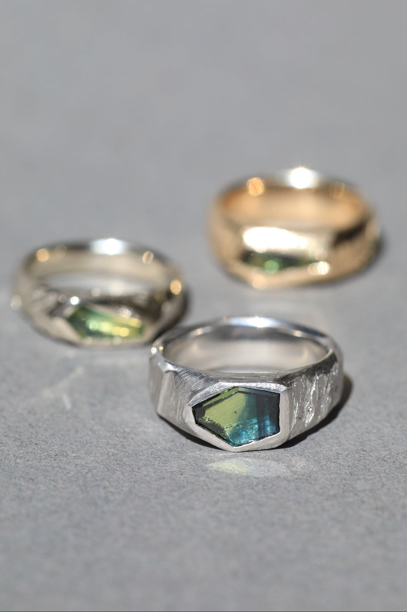 Irregular faceted green iridescent sapphire inlays on textured platinum and gold bands. Signet rings for men.