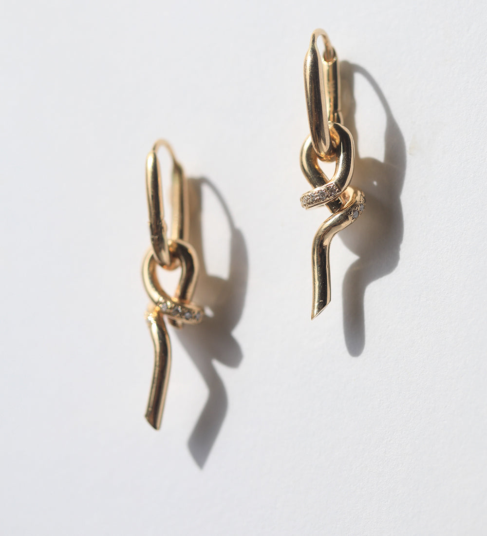 A loose knot pendant hangs from a hinged drop earring in 14k gold with pavé set diamonds.  Knot can also be worn as a pendant.