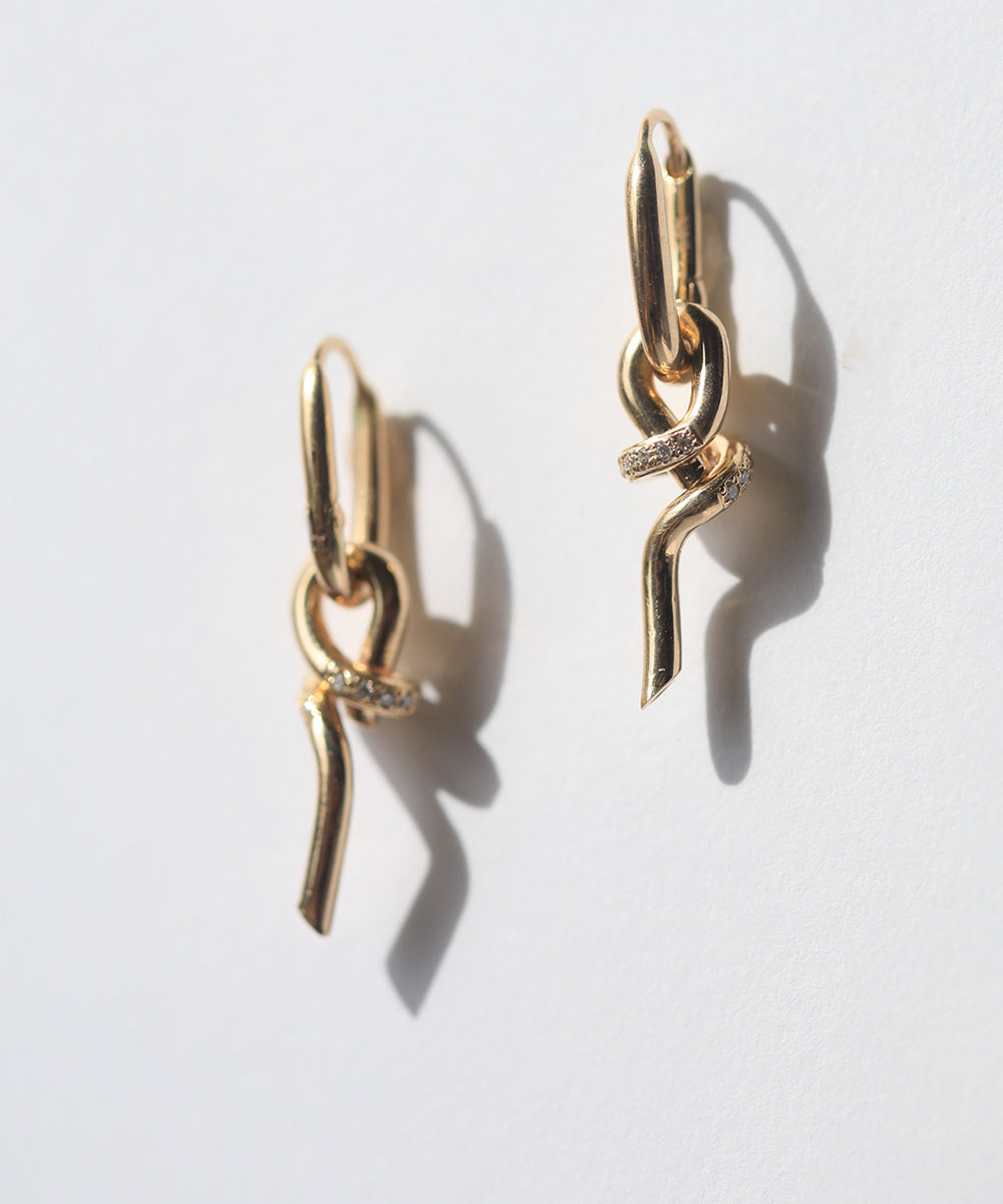 A loose knot pendant hangs from a hinged drop earring in 14k gold with pavé set diamonds.  Knot can also be worn as a pendant.