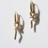 A loose knot pendant hangs from a hinged drop earring in 14k gold with pavé set diamonds.  Knot can also be worn as a pendant.