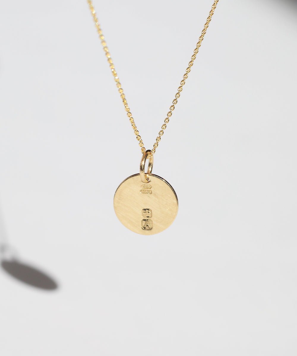 Circular Gold pendant featuring British hallmarks and date letter 'w' handcrafted macha studio brooklyn new york