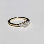handcrafted white diamond engagement ring featuring large cushion cut center stone accented with two pear shaped stones set in 14k yellow gold band macha studio brooklyn new york
