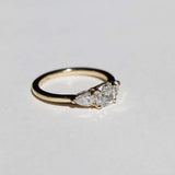handcrafted white diamond engagement ring featuring large cushion cut center stone accented with two pear shaped stones set in 14k yellow gold band macha studio brooklyn new york