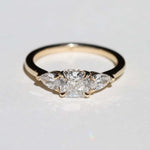 handcrafted white diamond engagement ring featuring large cushion cut center stone accented with two pear shaped stones set in 14k yellow gold band macha studio brooklyn new york