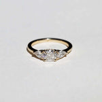 handcrafted white diamond engagement ring featuring large cushion cut center stone accented with two pear shaped stones set in 14k yellow gold band macha studio brooklyn new york