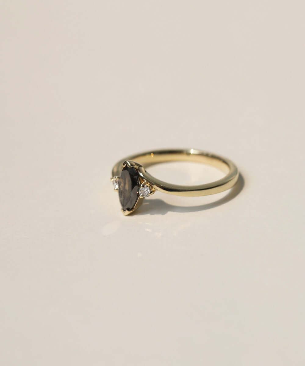 marquise cut salt and pepper diamond with dark warm tones, accented by white diamonds, set in 14k yellow gold
