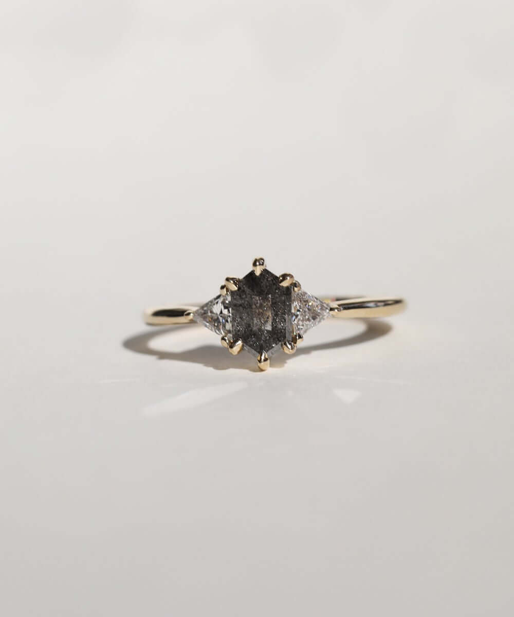 elongated hexagonal cut salt and pepper diamond accented with aligned trillion cut white diamonds
