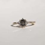 elongated hexagonal cut salt and pepper diamond accented with aligned trillion cut white diamonds